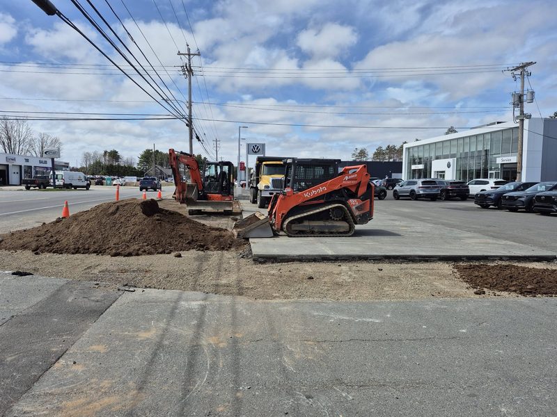 Excavator and skid steer landscaping the grounds of a commercial lot