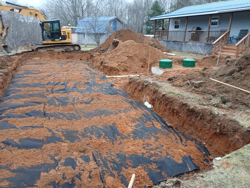 Septic bed built up over a membrane beside a rural home