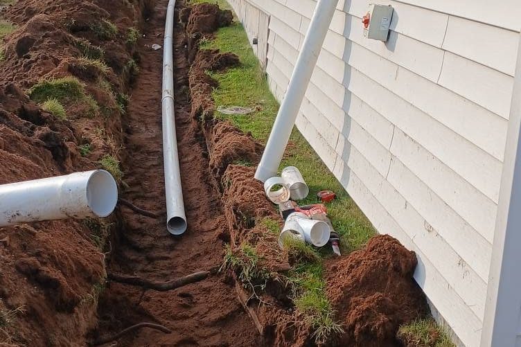 Drainage pipe laid in an open trench along a house foundation